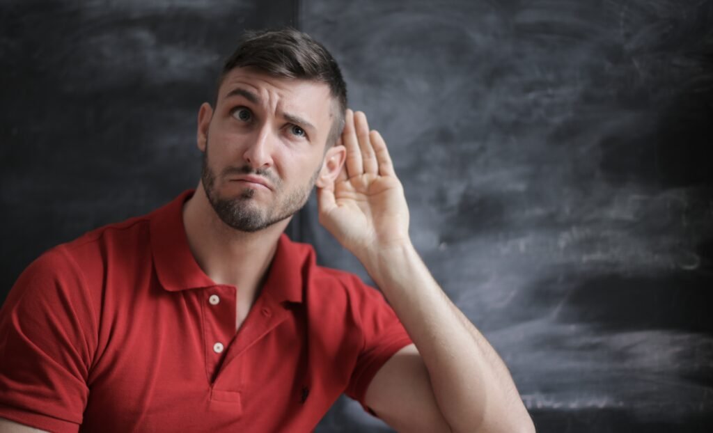 man cupping his ear to listen